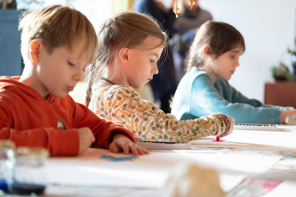 Kinder malen konzentriert während einem Kindergeburtstag